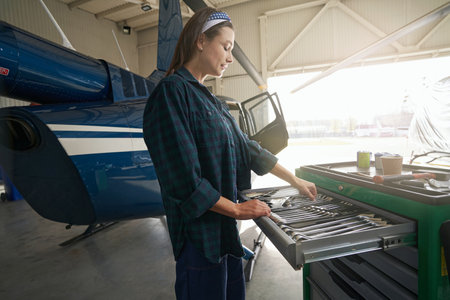 Elegant woman working with special hand tools in aviation hangarの写真素材