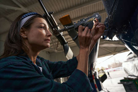 Brunette Caucasian woman air frame mechanic working in aviation garageの写真素材