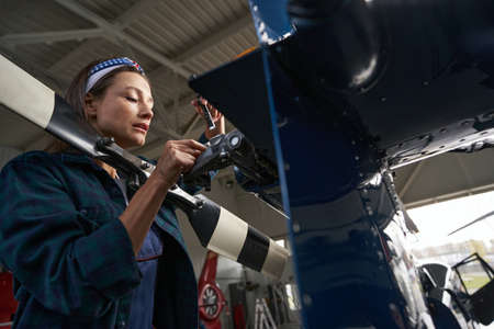 Gorgeous woman wearing uniform fixing the engine of the aircraft in hangarの写真素材