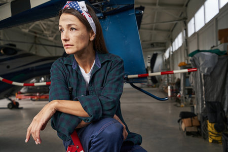 Thoughtful elegant Caucasian repairwoman mechanic in hangarの写真素材