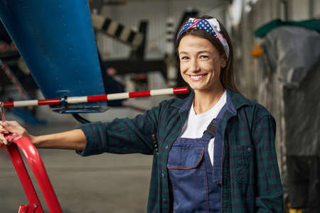 Joyful Caucasian woman repairwoman posing at the photo camera in hangarの写真素材