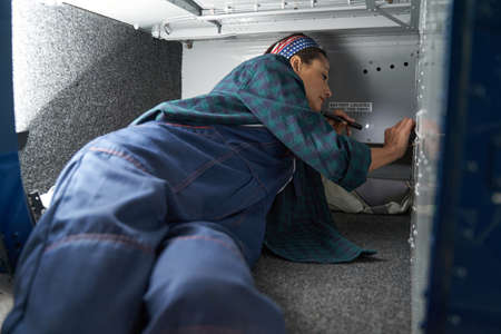 Focused brunette female aviation engineer analyzing airplane parts inboardの写真素材