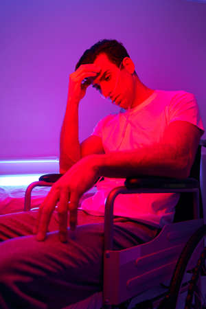 Man sitting in the room with pink lightの写真素材