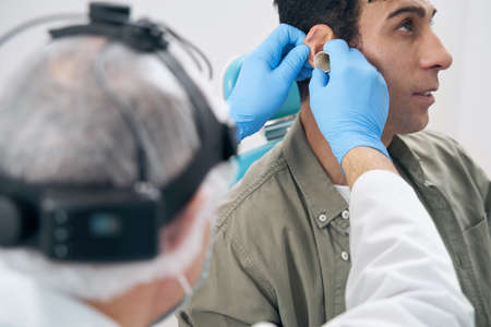 Close-up photo of otorhinolaryngologist and man in the doctor officeの写真素材