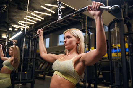 Concentrated blonde female person training in the gym
