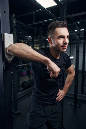 Positive delighted brunette male standing near chin-up bar