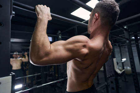 Close up of young athlete pulling up on horizontal bar