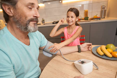Girl measures the pressure of a man at the kitchen