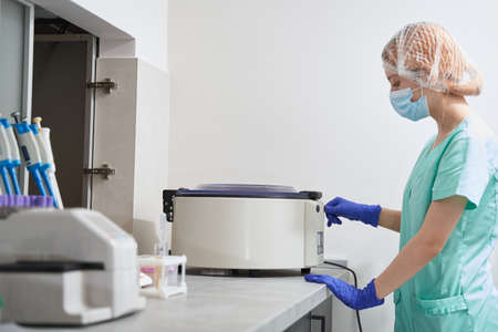 Lady prepearing for medical research with centrifuge in hospital