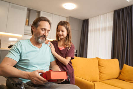 Man in a wheelchair holding a gift from a girl