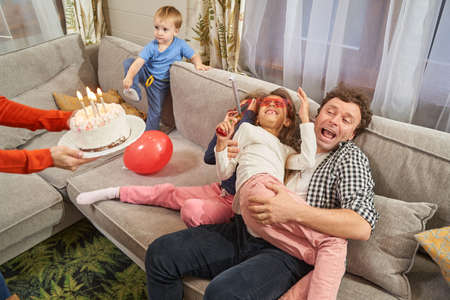 Funny family celebrating birthday with cake at home