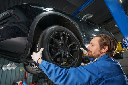 Man holding car wheel and making diagnosisの写真素材