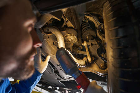 Car mechanic holding lamp and performing machine diagnosticsの写真素材