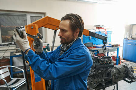 Male holding tool in hands and looking at itの写真素材