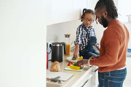 African American male cooking in the kitchen with his young daughterの写真素材