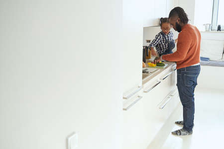 Caring male spending time in the kitchen with his daughterの写真素材
