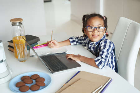Little girl sitting at her desk with laptop and book