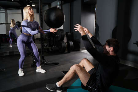 Lady exercising in the fitness club with coach