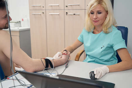 Smiling doctor using madical gadgets for man check-up