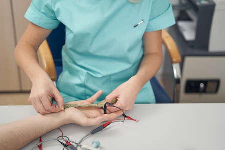 Female physician examining male patient hand in office