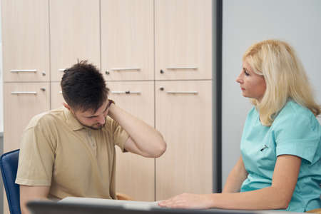 Young man complaining on headache to practitioner