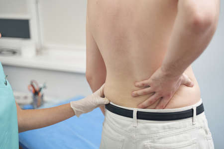 Man complaining on pain in back to doctorの写真素材