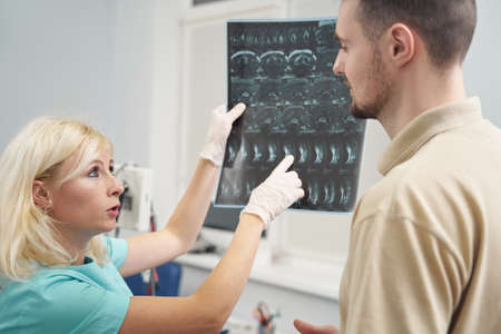 Female doctor showing spine x-ray to young man