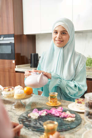 Happy Muslim woman sitting at the kitchen tableの写真素材