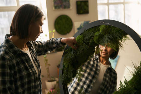 Florist gluing green plant on round mirror