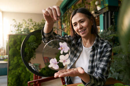 Lady holding elegant round glass with flowersの写真素材