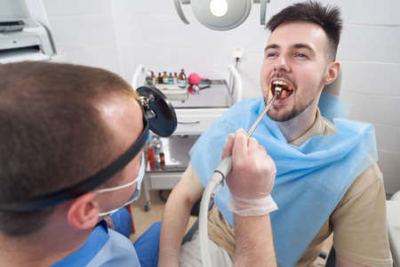 Young man with sore throat visiting doctorの写真素材