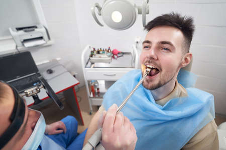 Smiling man with sore throat visiting otorhinolaryngologist