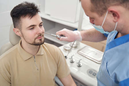 Otorhinolaryngologist using medical tools in patient nosetril