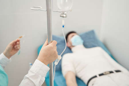 Man during in bed drip procedure in hospitalの写真素材