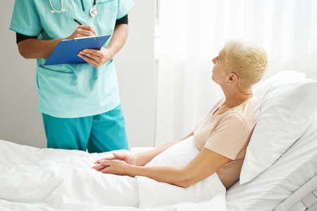 Physician taking notes while communicating with patient