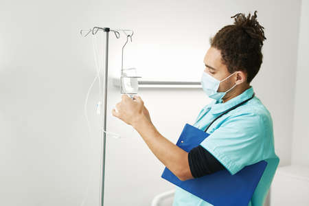 Medical worker putting bottle into IV drip applianceの写真素材