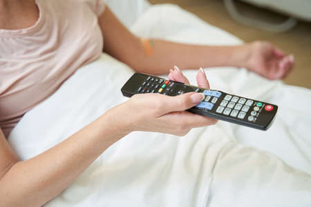 TV remote in hand of aged hospital patientの写真素材