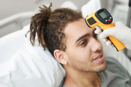 Infrared thermometer measuring temperature of male patientの写真素材