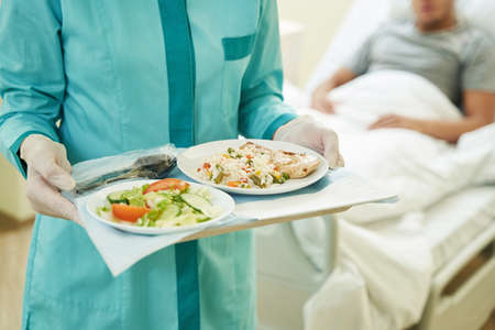 Medical person keeping tray with food in hospitalの写真素材