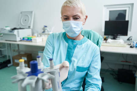Woman in mask doing blood tests in laboratory
