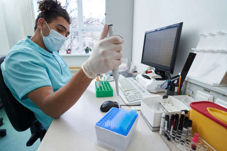 Young male laborant working with samples before computer