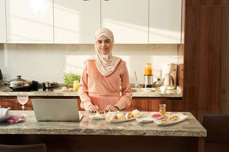Muslim woman cooking and using laptop at homeの写真素材