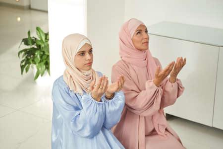 Muslim women in hijab praying at home