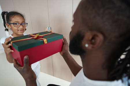 Adult African American father is giving gift to his daughter