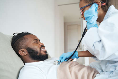 Girl in a medical gown listens to breath of father with stethoscopeの写真素材