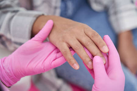 Doctor in pink sterile gloves is holding hand of patientの写真素材