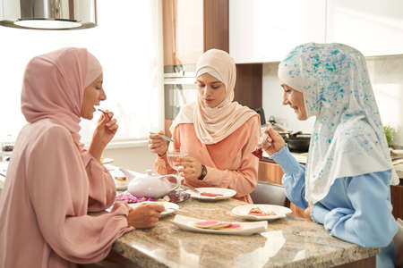 Muslim women having dinner together in kitchen