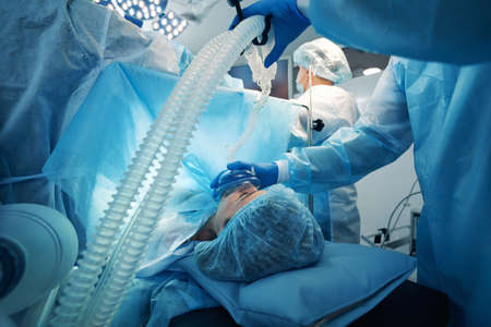 Surgeon pressing mask of oxygen-breathing apparatus to patient face
