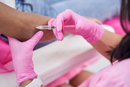 Doctor makes injection in elbow area on arm of clientの写真素材