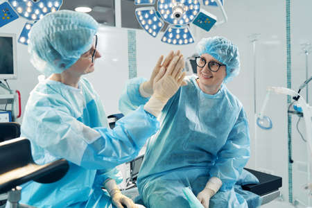 Nurses giving high five to each other on operation bed